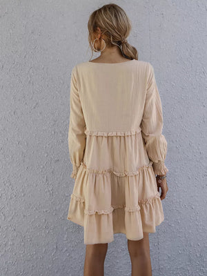 Apricot ruffled mini dress with long sleeves and tiered skirt.