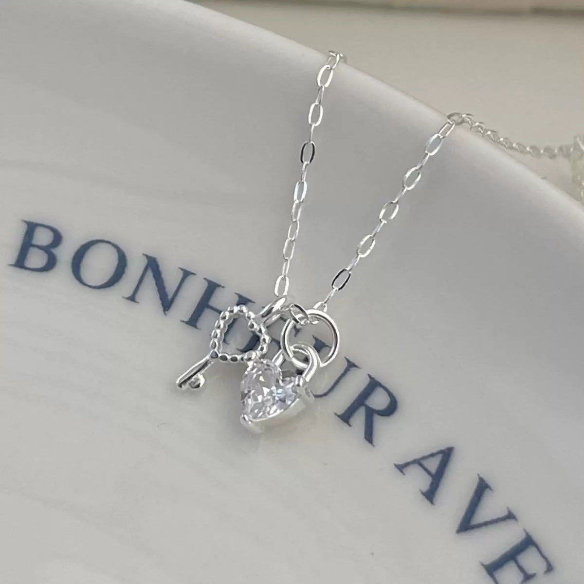 Sterling silver necklace with heart lock and key charms, featuring a cubic zirconia heart.