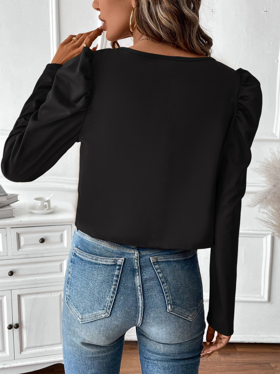 Black bolero jacket with puffed long sleeves and a zip-front closure.