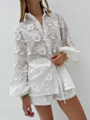 White embroidered two-piece shirt and shorts set with floral applique and button-down closure.