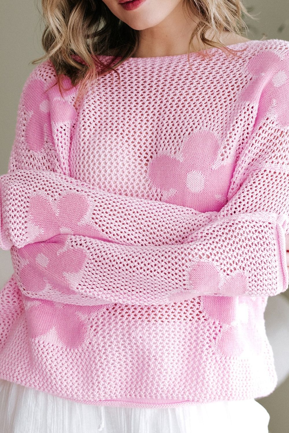 Openwork blush pink sweater with floral intarsia pattern and crew neck.