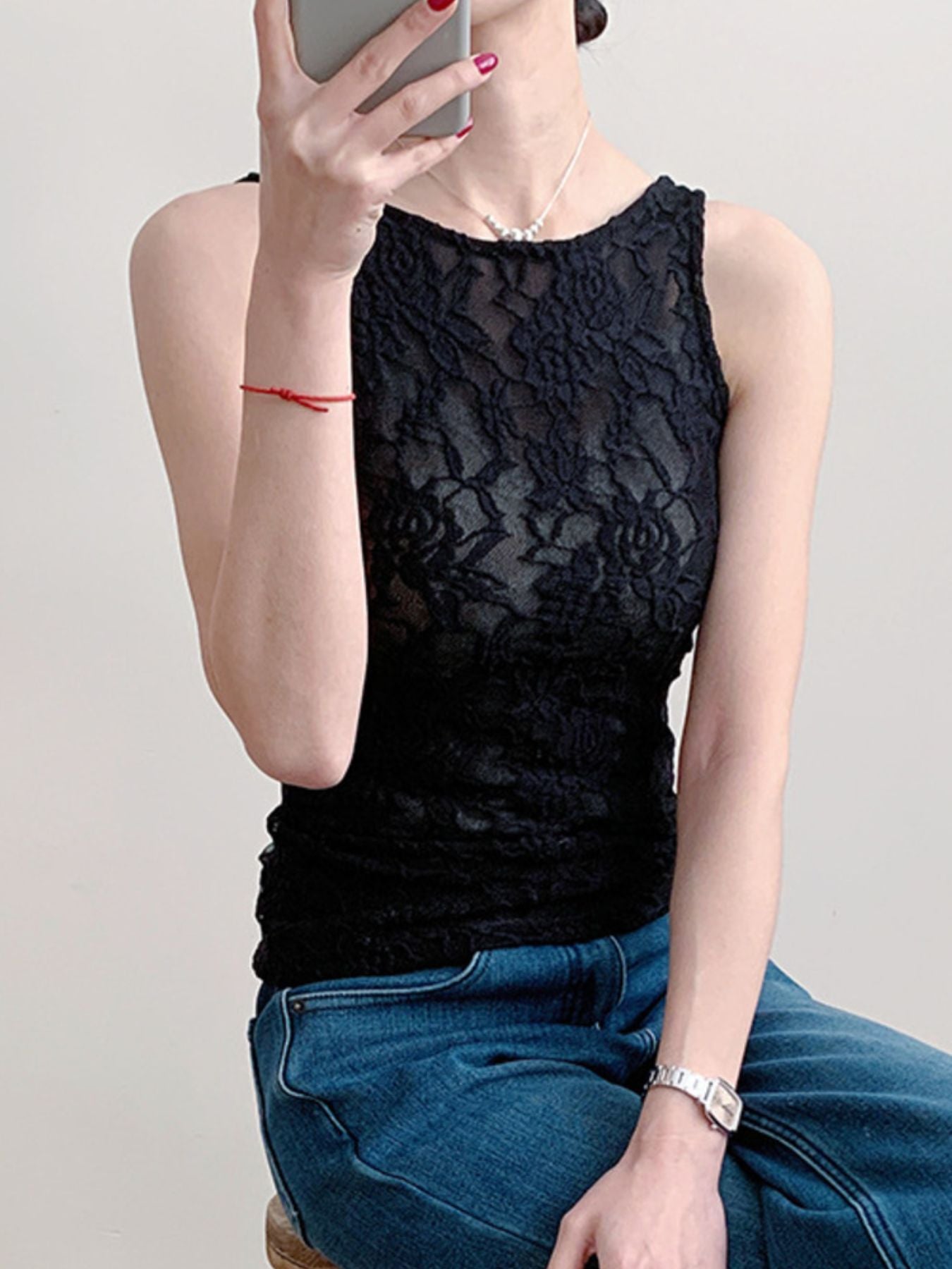Black lace tank top with sheer floral pattern and round neckline.