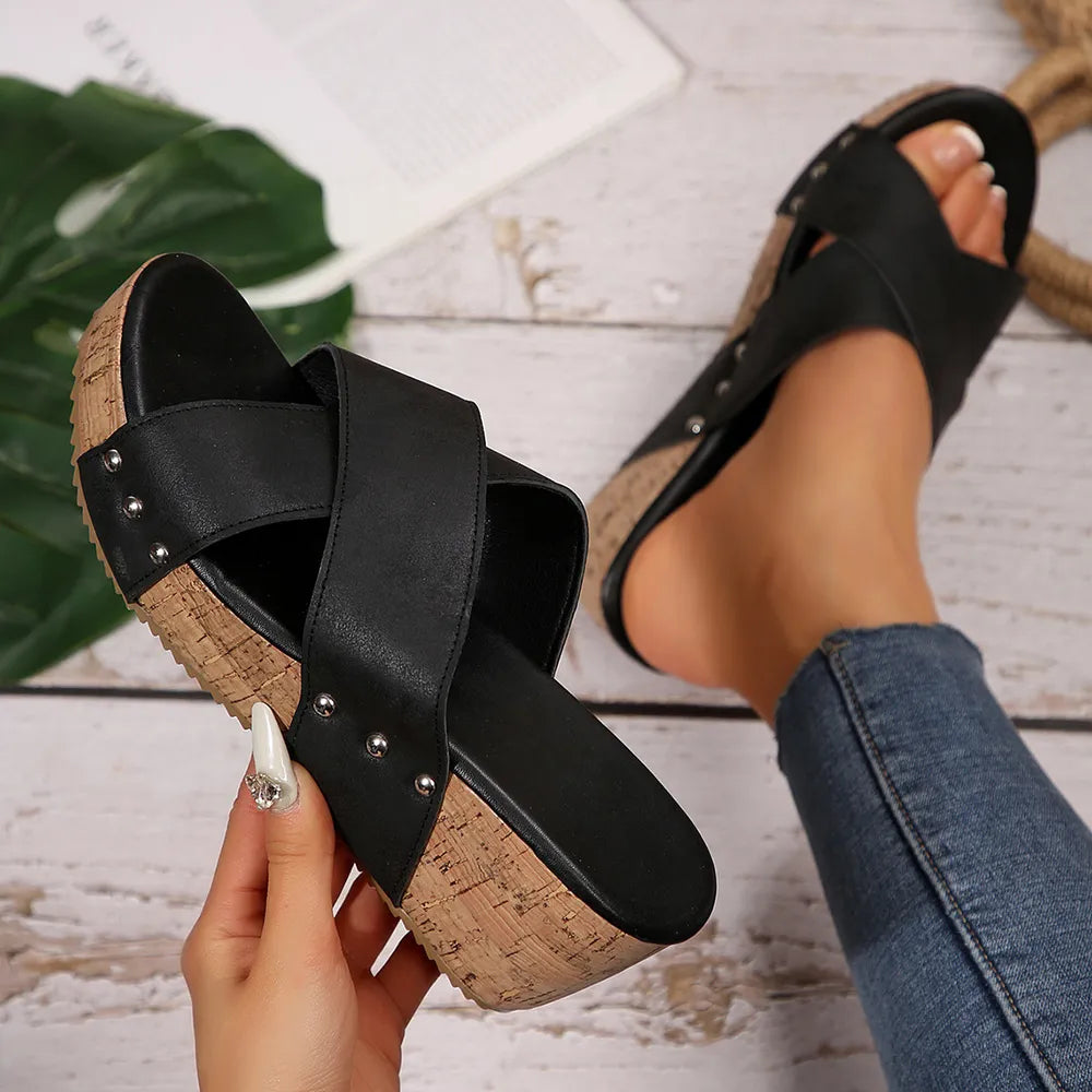 Black crisscross cork wedge slides with studded detail.