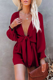 Burgundy tie knot romper with puff sleeves and a deep V-neck.