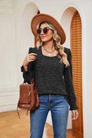 Textured black blouse with square neckline, ruffled cuffs, and long sleeves.
