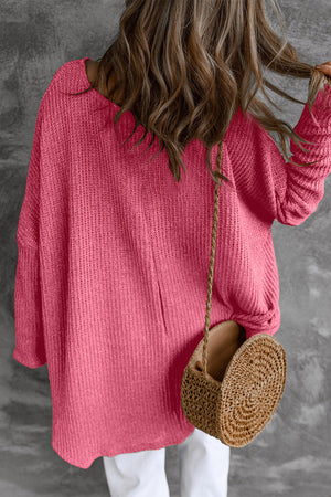 Asymmetric slouch knit top in strawberry acrylic with a relaxed fit and long sleeves.