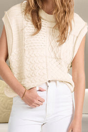 Ivory knit patchwork vest with cable and diamond patterns, mock neck, sleeveless.