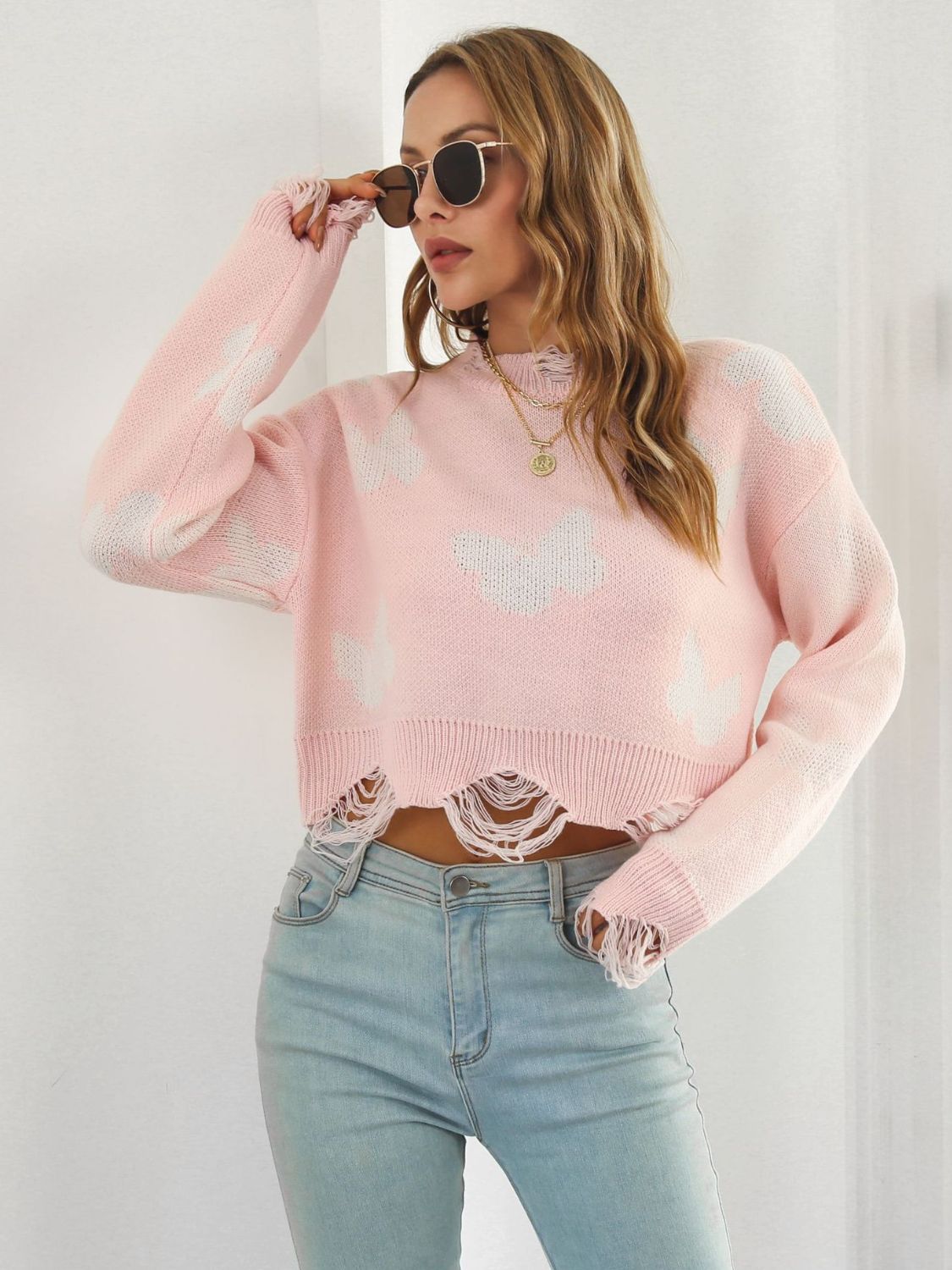 Blush pink knit cropped sweater with distressed details and white butterfly print.