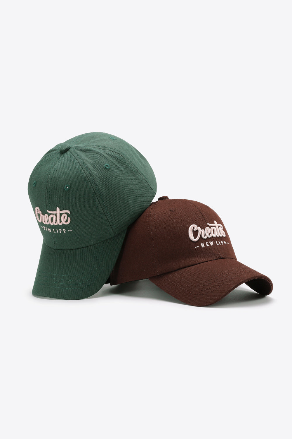 Green and Burnt Umber baseball caps with embroidered "Create New Life" text.