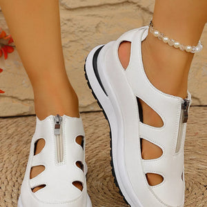 White cutout wedge sneakers with zipper detail and chunky sole.