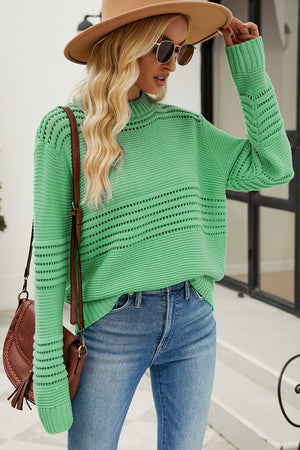 Green open-knit mock neck sweater with horizontal cutout details and textured sleeves.