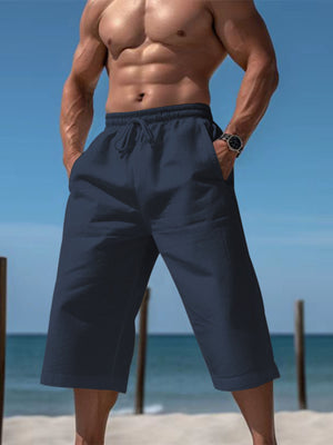 Navy drawstring cropped sweatpants with pockets on a man at the beach.