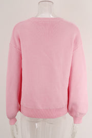 Blush pink acrylic knit sweater with graphic bow intarsia detail and crew neck.
