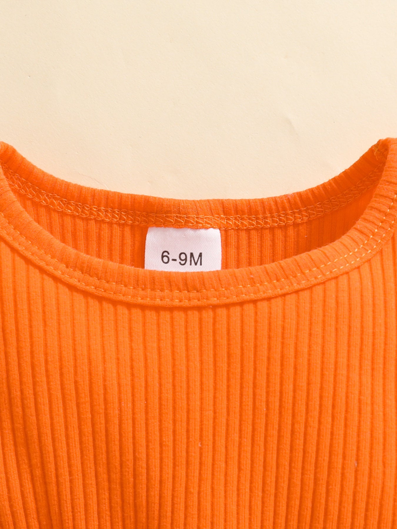 Orange-red ribbed baby set with a size tag.