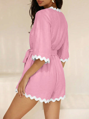 Pink maternity wrap romper with 3/4 sleeves and scalloped trim.