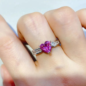 Silver ring with a pink heart-cut gemstone and baguette accents.