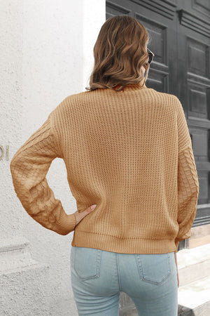 Camel cable knit turtleneck sweater with chevron detail on sleeves.