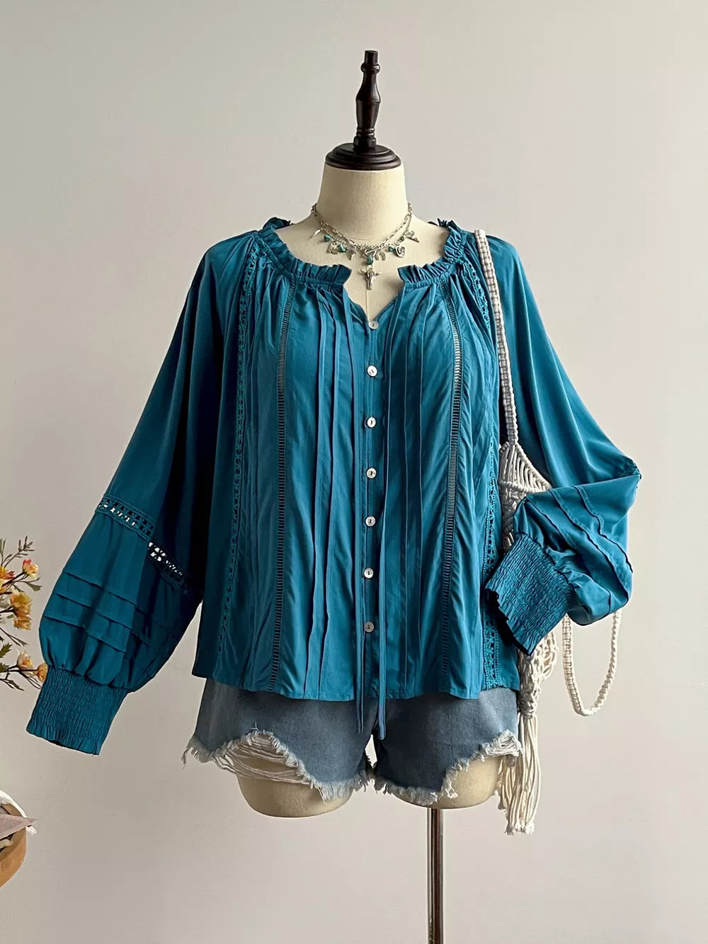 Teal ruffled lantern sleeve blouse with button-down front and crochet trim.