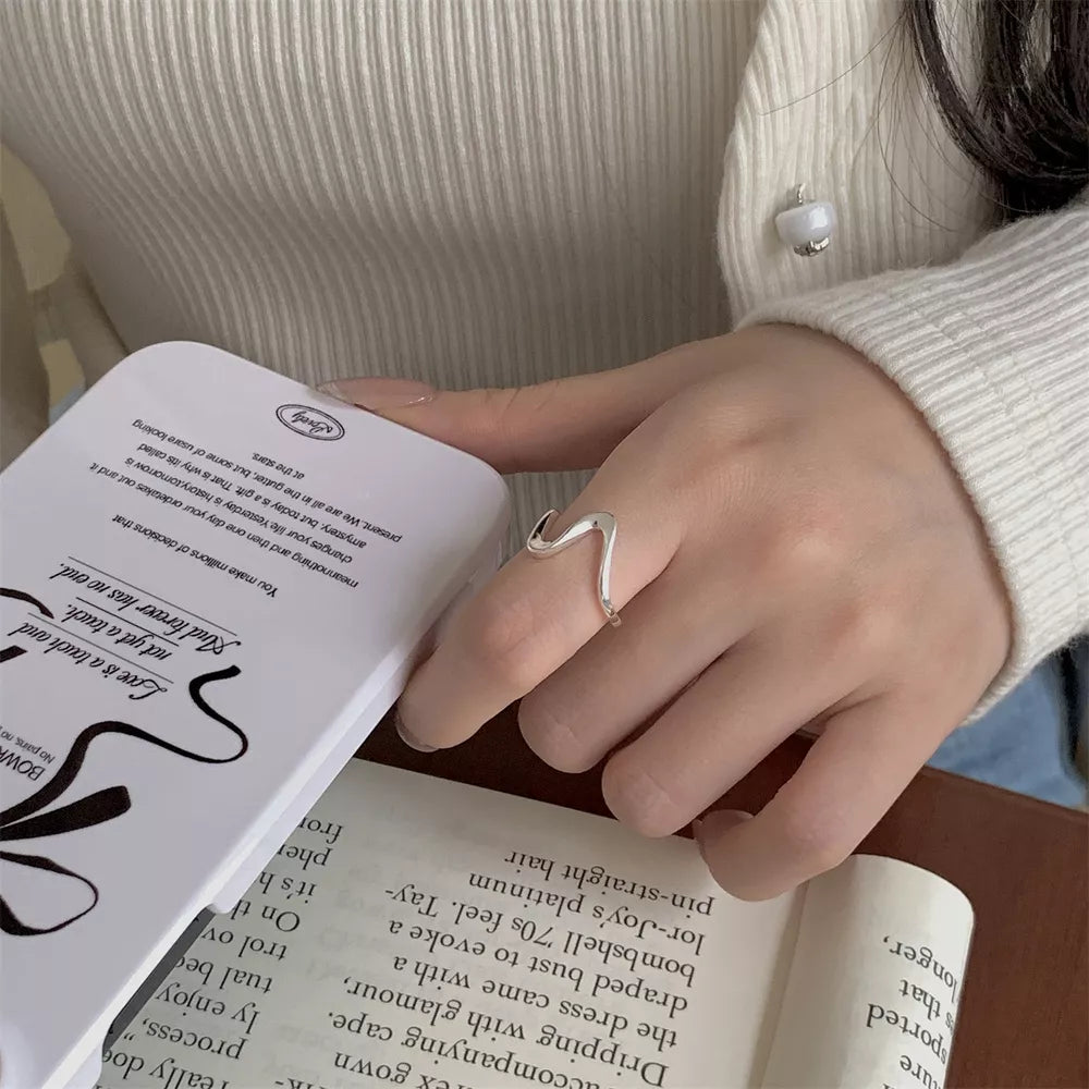 Sterling silver ring with a wavy minimalist design on a woman's finger.