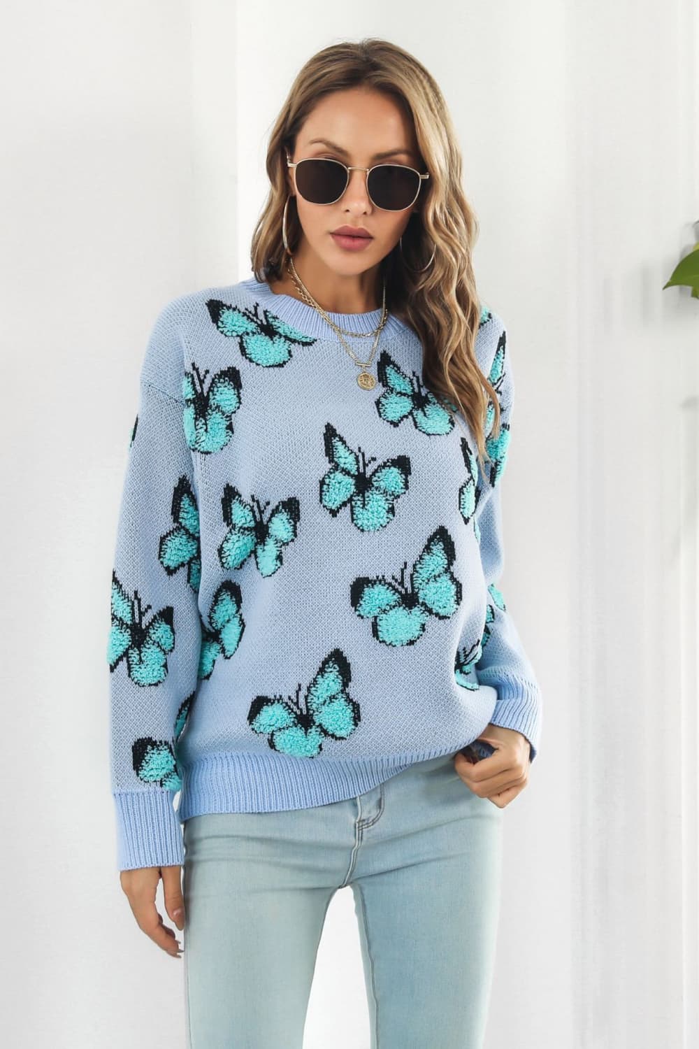 Pastel blue knit crewneck pullover sweater with allover butterfly motif.