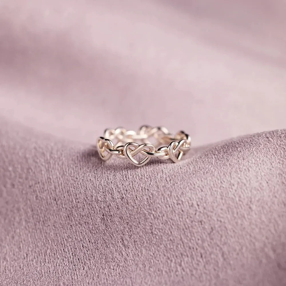 Sterling silver ring with intertwined heart motif, delicate and classic design.