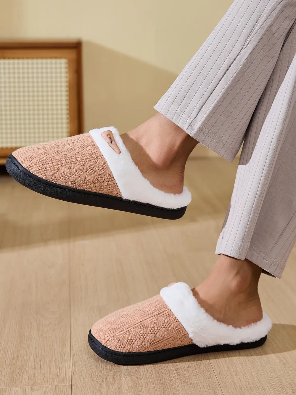 Cable knit house slippers in tan with white shearling lining and a button detail.