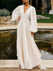 White maxi dress with textured pattern, deep V-neck, and dramatic balloon sleeves.