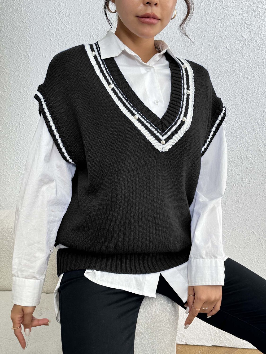 Black acrylic knit vest with v-neck, varsity stripes and pearl trim detail.