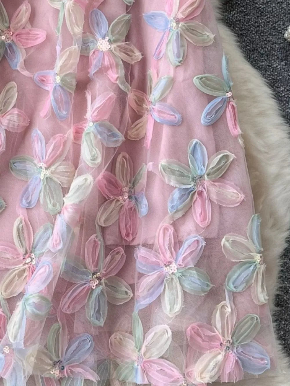 Pink layered skirt with embroidered pastel floral appliques and sequin details.