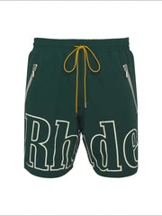 Dark green cargo shorts with white logo print, yellow drawstring, and zippered pockets.
