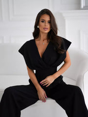 Black surplice wide-leg romper with deep V-neck and cap sleeves.