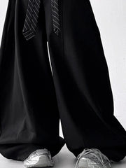 Men's black wide leg drawstring sweatpants with a striped tie detail.