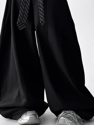 Men's black wide leg drawstring sweatpants with a striped tie detail.