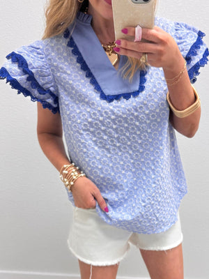 Light blue cotton eyelet embroidered blouse with flutter sleeves and lace trim.