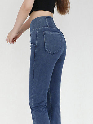Medium wash denim jeans with crossover waist and flare leg, detailed view of back pockets.