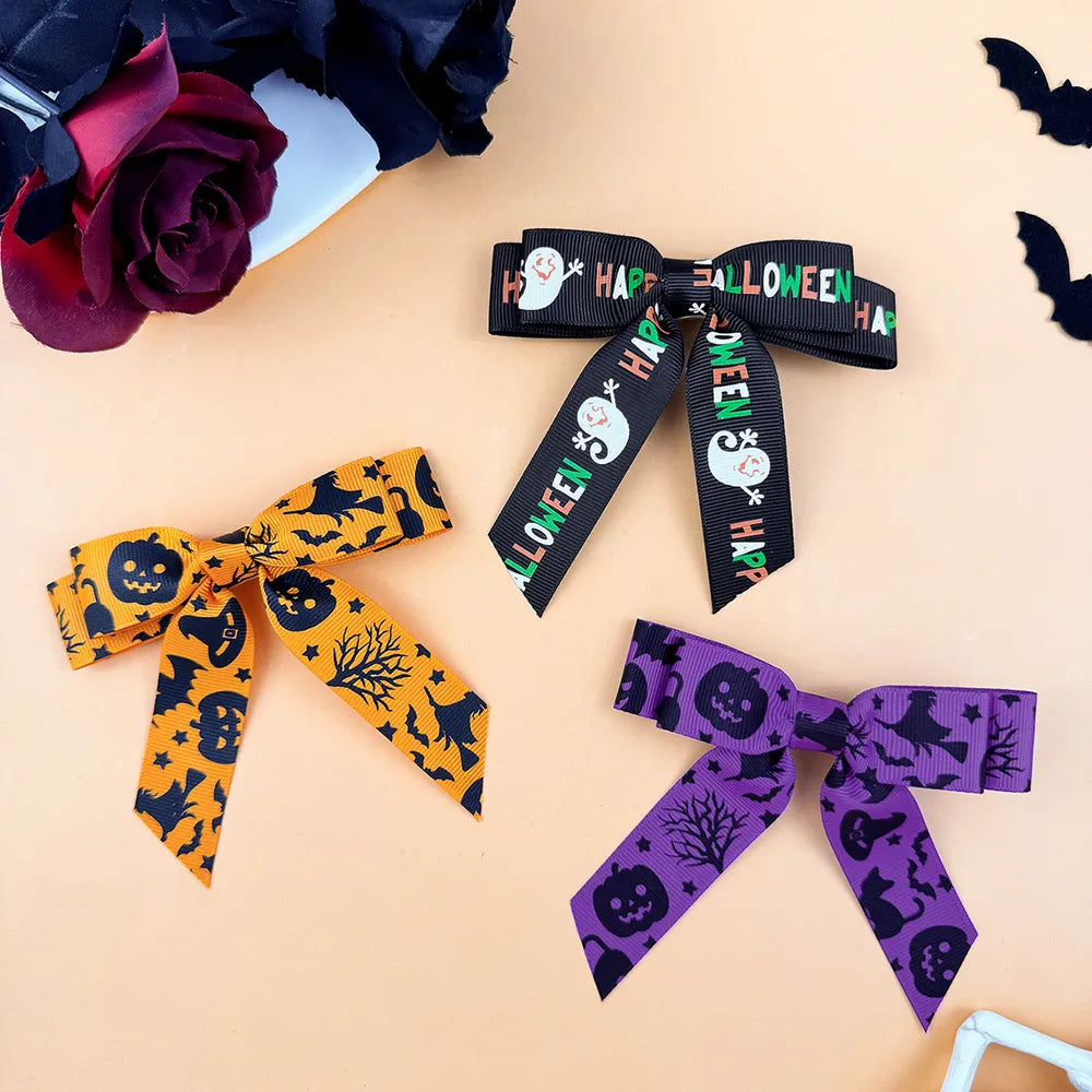 Halloween print bow hair clips in black, tangerine, and violet with spooky motifs.