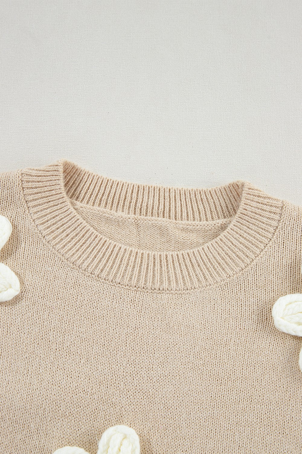 Tan knit sweater with embroidered white blooms, crew neck, acrylic.