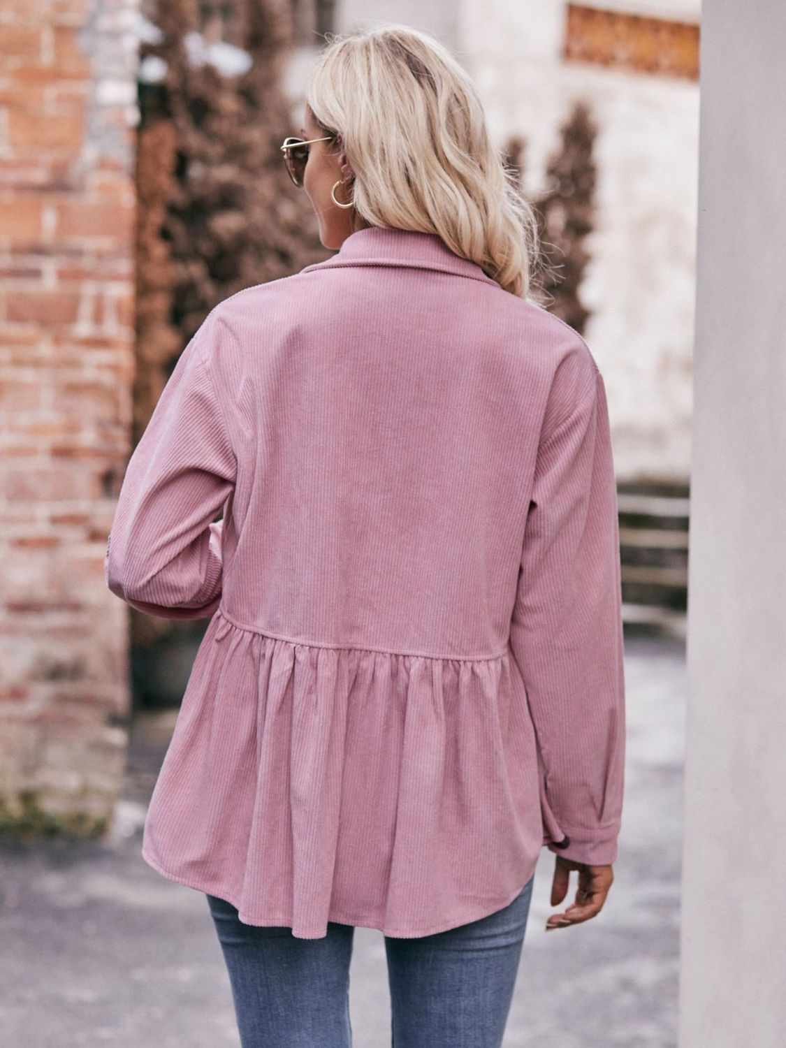 Pink corduroy peplum shirt jacket with buttoned cuffs and a ruffled hem.