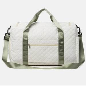 White quilted duffel bag with olive accents and a zippered front pocket.