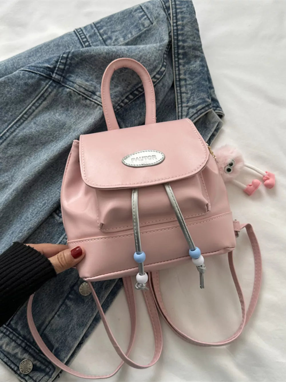 Pink leather mini drawstring backpack with beaded details and cute charm.