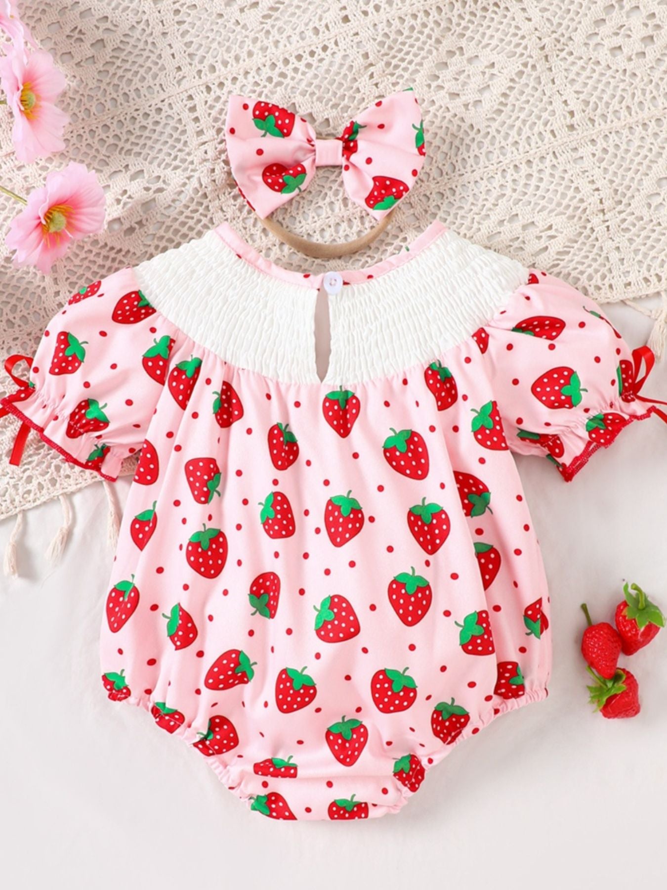 Baby pink strawberry print smocked one-piece with puff sleeves and matching headband.