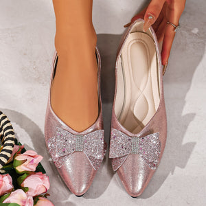 Pink pointed toe flats with dazzling glitter bows and rhinestone accents.