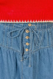 Denim a-line skirt with button front, tie waist, and ruffle hem.