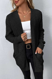 Black waffle knit longline cardigan with pockets and open front, styled with a white crop top and black jeans.