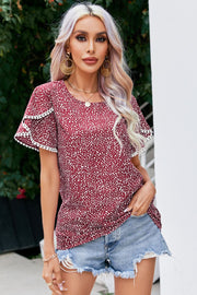 Burgundy dotted blouse with flutter sleeves and pom-pom trim.