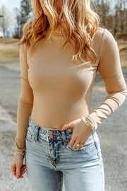Sand ribbed turtleneck bodysuit with long sleeves, styled with jeans.