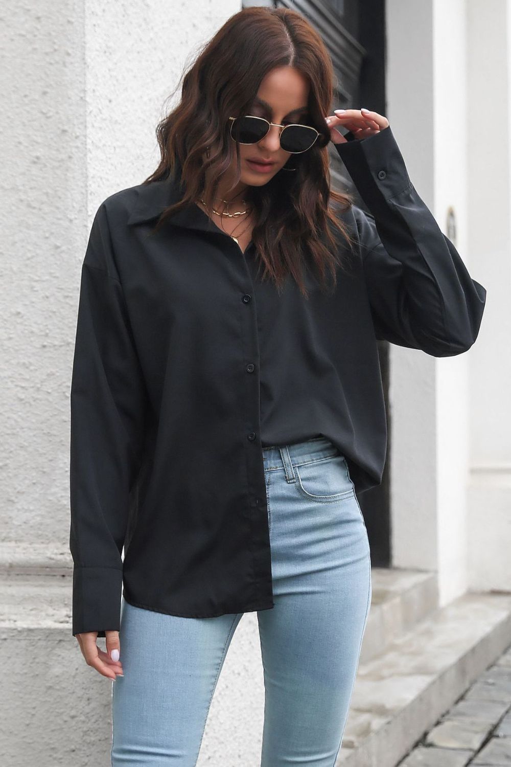 Oversized black cotton poplin shirt with button front and collar, styled with light wash jeans.