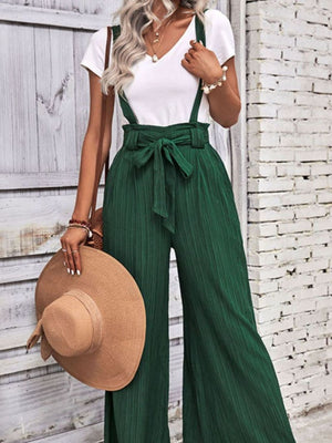 Dark green wide-leg suspender jumpsuit with tie waist and textured fabric.