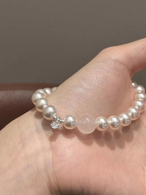 Pearl charm bracelet with zircon and pink stone detail on a wrist