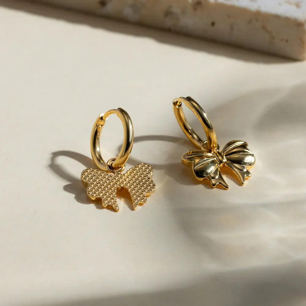 Gold hoop earrings with detailed bow charms, 18K gold-plated.